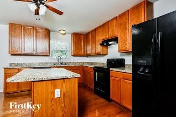 Wentzville house for rent - A kitchen with wooden cabinets and a black refrigerator.