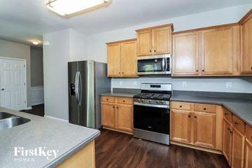 Dallas house for rent - a kitchen with wooden cabinets and stainless steel appliances