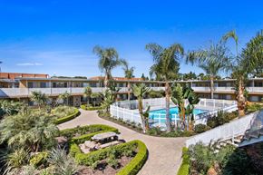 Buena Park apartment for rent - a building with a pool and palm trees in front of it