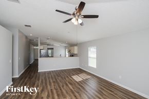 Palm Bay house for rent - an empty living room with a ceiling fan and a kitchen