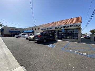 Orange apartment for rent - a hair salon with cars parked in front of it