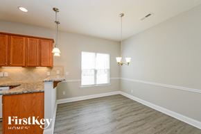 Kernersville house for rent - an empty kitchen and dining room with wood flooring and white walls