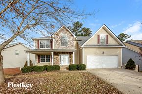 Dallas house for rent - A house with a garage and a tree in front of it.