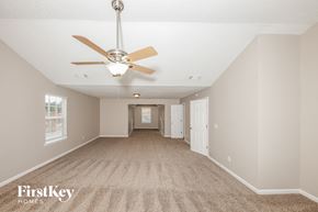Dallas house for rent - A spacious room with a fan and carpeted floor.