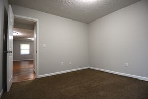 Terre Haute triplex for rent - an empty living room with carpet and a door to a bedroom