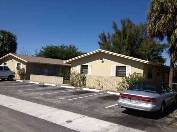 Oakland Park apartment for rent - A silver car is parked in a parking lot in front of a yellow building.
