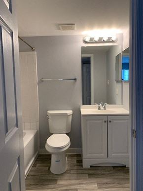Laurel apartment for rent - A white toilet is in a bathroom with a white sink and a mirror.