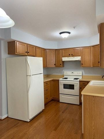 Laurel apartment for rent - A kitchen with a white refrigerator, white stove, and wooden cabinets.