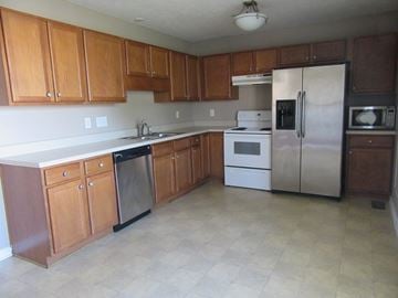 Fayetteville house for rent - A kitchen with wooden cabinets and a white fridge.