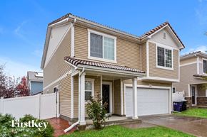 Denver house for rent - a tan house with a white fence and a driveway