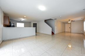 Denver house for rent - a large empty living room with a white tile floor and a ceiling fan