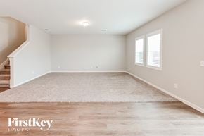 Brookshire house for rent - A spacious room with a staircase on the left and a rug on the floor.