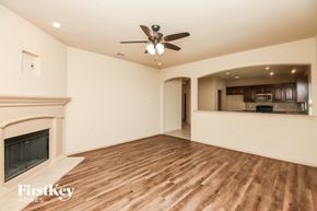 Weatherford house for rent - an empty living room with a fireplace and a ceiling fan