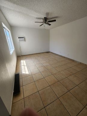 Tucson house for rent - an empty living room with a ceiling fan and tiled floors