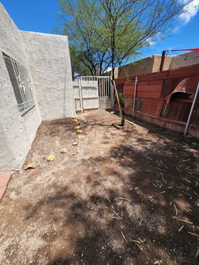 Tucson house for rent - an empty yard with a white fence and a white brick building