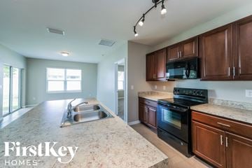 Cape Coral house for rent - a kitchen with wooden cabinets and granite counter tops and a sink