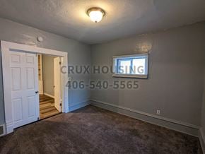 Great Falls house for rent - A room with a doorway leading to another room and a sign that says "CRUX HOUSING" with a phone number on the wall.