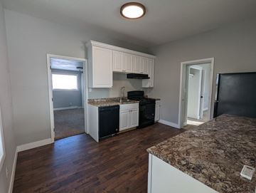 Great Falls house for rent - a kitchen with white cabinets and granite counter tops and a black stove
