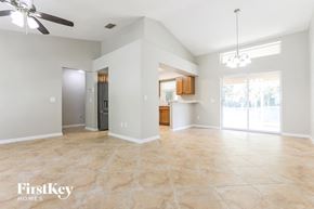 North Port house for rent - an empty living room with a kitchen and a ceiling fan
