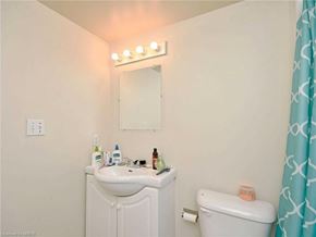 Waterloo apartment for rent - A bathroom with a white sink and toilet, a mirror with lights above it, and a blue shower curtain.