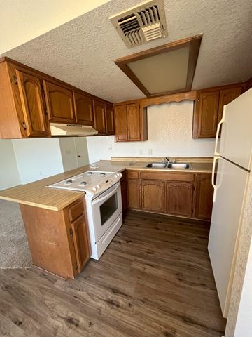 Cottonwood apartment for rent - A kitchen with a white fridge, white stove and wooden cabinets.