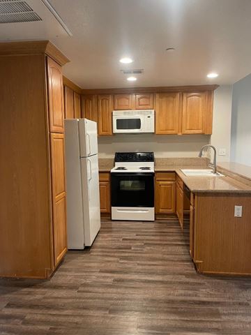 Riverside apartment for rent - A kitchen with wooden cabinets and a white refrigerator.