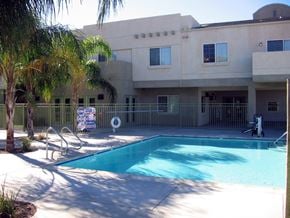 Riverside apartment for rent - A pool in front of a building with a palm tree.