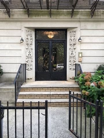 Brooklyn apartment for rent - A black wrought iron gate is in front of a white building with a black door.