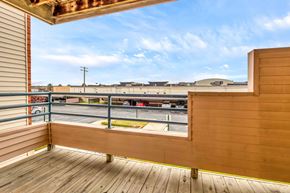 Shelby Township apartment for rent - A wooden deck with a view of a parking lot and buildings.
