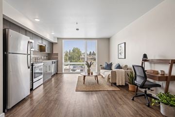 Seattle apartment for rent - A modern kitchen with a refrigerator, a dining table with chairs, and a living area with a couch.