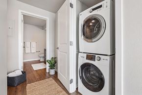 Seattle apartment for rent - Stacked white washer and dryer in an open closet next to a bathroom doorway.