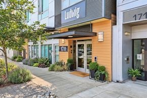 Seattle apartment for rent - Street-level entrance of Ludwig Apartments with modern signage, awning, planters, and sidewalk landscaping.
