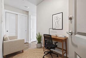 Seattle apartment for rent - Work nook with wooden desk, mesh chair, armchair, and sliding closet doors at Ludwig Apartments.