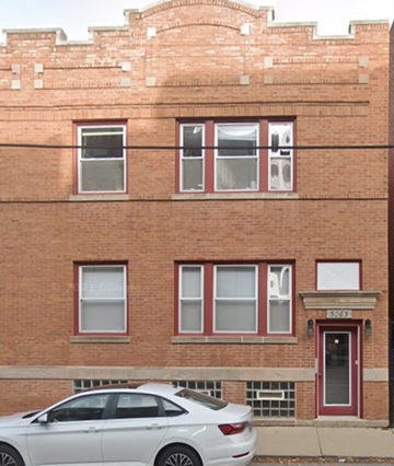 Chicago apartment for rent - A white car is parked in front of a red brick building.