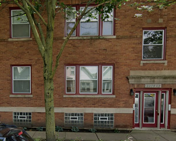 Chicago apartment for rent - a brick building with red windows and a tree in front