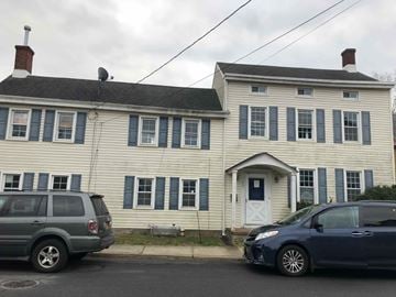 Hamilton apartment for rent - A white house with a blue car parked in front.