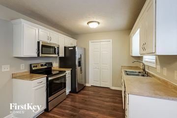 Clarksville house for rent - A kitchen with white cabinets and a wooden counter top.