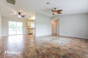 Port Charlotte house for rent - an empty living room with two ceiling fans and a kitchen