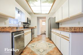 Port Charlotte house for rent - a kitchen with white cabinets and granite counter tops and stainless steel appliances