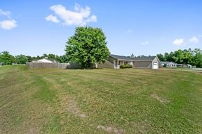 Jacksonville house for rent - A large grassy field with a house and a tree in the distance.