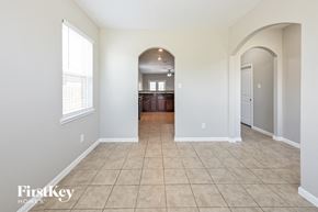 Hockley house for rent - A spacious room with beige tiled flooring and a large arched doorway leading to another room.