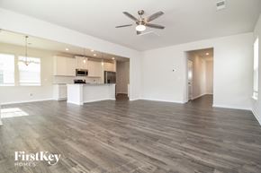 Simpsonville house for rent - an empty living room with a kitchen and a ceiling fan