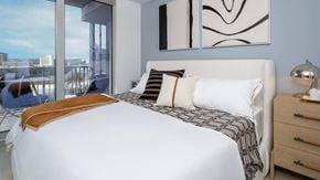 Austin apartment for rent - A bedroom with a large bed, a chair, and a window overlooking a cityscape.