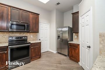 Fort Worth house for rent - a kitchen with stainless steel appliances and wooden cabinets