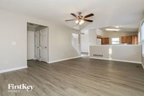 Lebanon house for rent - A spacious room with a ceiling fan and light fixture, wooden flooring, and a staircase leading to another room.