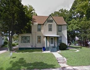Magnolia apartment for rent - A two-story house with a green front door and steps.