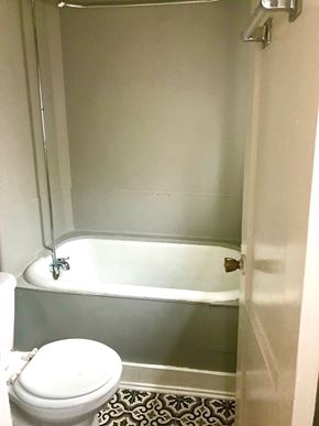 Tulsa house for rent - A white toilet sits next to a bathtub in a bathroom.