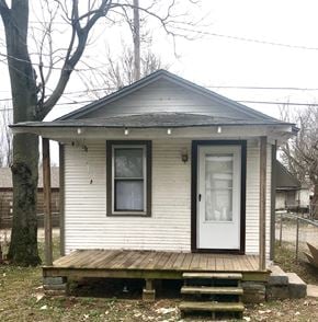 Tulsa house for rent - A small white house with a brown door and a porch.