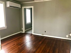 Tulsa house for rent - A room with wooden flooring and a door leading to a hallway.