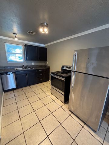 Tulsa apartment for rent - A kitchen with black cabinets and a stainless steel refrigerator.